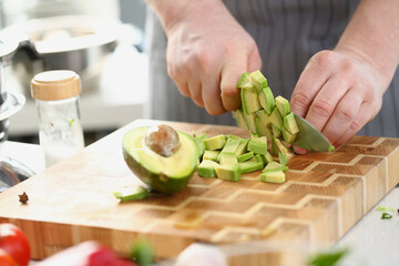 Closeup of knife with avocado slices on cutting board at home. Cooking avocado in different dishes