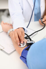 Cardiologist doctor measures blood pressure to patient with tonometer in clinic. Diagnosis of...