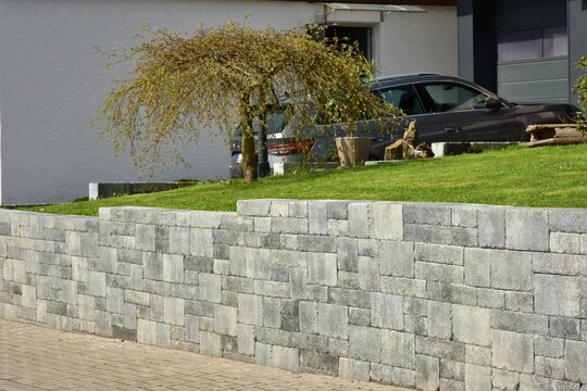 Mauer aus Betonsteinen um ein Wohnhaus mit Gartengrundst&uuml;ck
