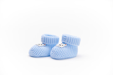 A pair of handmade blue knitted baby booties, isolated on white background. Newborn clothing and pregnancy concept. Copy space for advertising text. Fashion.