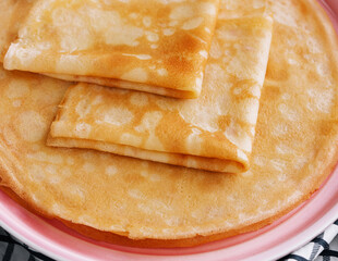Stack of fresh thin pancakes on pink plate