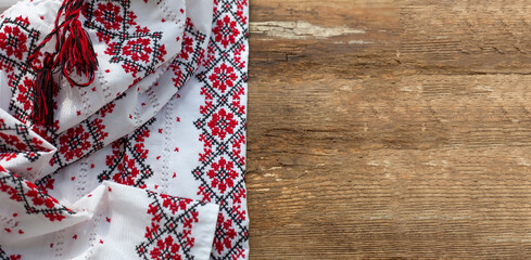 Ukrainian clothes embroidered white shirt. Red and black threads on a wooden background. Vyshyvanka is a symbol of Ukraine. Embroidery copy space. Cross stitching.