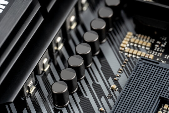 Macro shot of VRM MOSFETs and Capacitor (Voltage Regulator Module) on a modern motherboard. Mosfets, Solid-state capacitors, Chokes, Field-effect transistors, VRM. Technological background.
