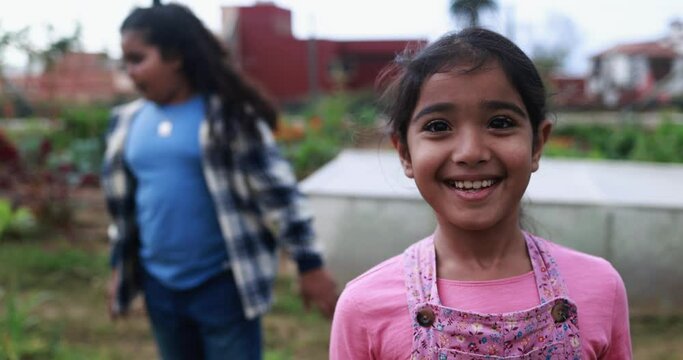 Indian girl smiling in front of camera outdoor with organic vegetables garden in background