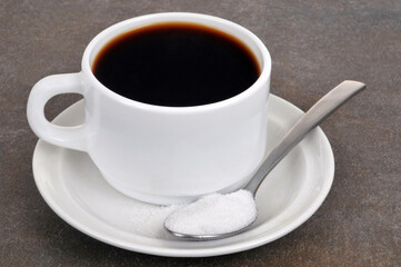 Tasse de café avec une cuillère de sucre en poudre sur fond gris