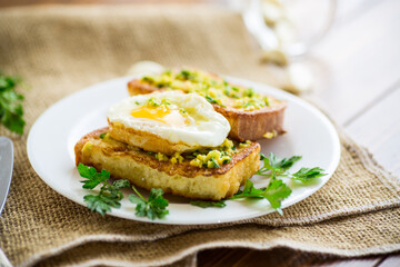 Fried croutons in batter with garlic and herbs and a fried egg in a plate.