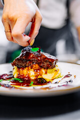 Chef decorated Stewed veal cheeks with mashed potatoes on restaurant kitchen