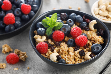 Dry granola with blueberries, raspberries and nuts on grey background . Healthy breakfast meal