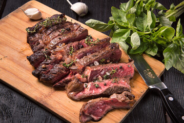 Fried ribeye steak cut into pieces on a wooden board.