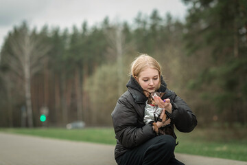 A beautiful young blonde girl walks a purebred Toy Terrier in cloudy weather.