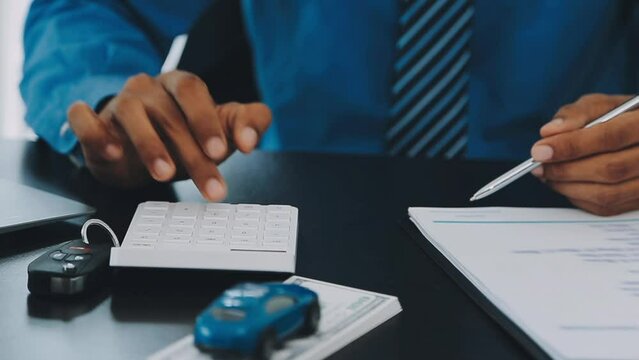 Closeup of Asian female signing car insurance document or lease paper contract or agreement. Buying or selling new or used vehicle with car keys on table.