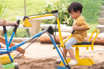 Kid baby boy todler playing construction truck toy diging sand in playground
