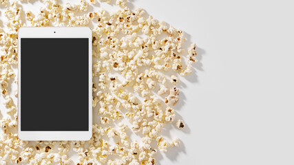 Scattered popcorn and tablet computer with blank screen for your design
