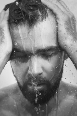 Monochrome image of young frustrated man under shower