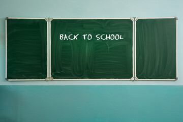 Text back to school is drawing by chalk on green blackboard in class. Education and knowledge concept.