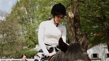 Young adult beautiful woman in helmet learning Horseback Riding, equestrian sport.Active lifestyle and leisure activity concept