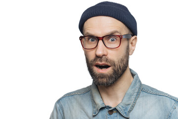 Suprised terrified unshaven male stares at camera and keeps mouth widely opened, wears fashionable...