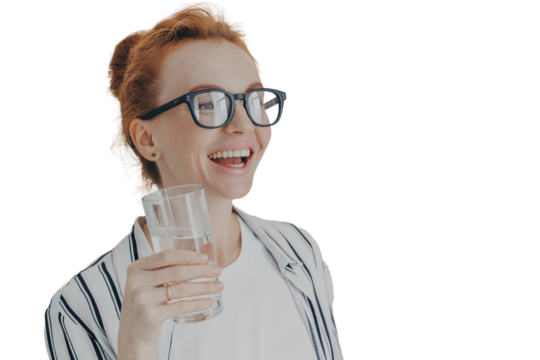 Happy laughing ginger woman standing in kitchen in morning with glass of pure mineral water