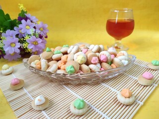 Gemrose biscuits on a transparent plate on a light background. Gemroses are round biscuits topped with colorful sugar flowers.