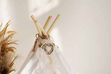 White fabric tepee top with decorative wood hearts and white feathers dream catcher with copy space. © July P