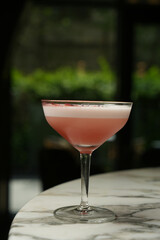 Red cocktail in martini glass with froth, close-up