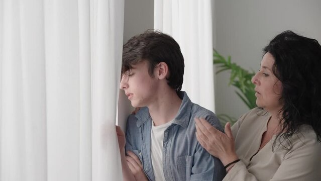 Woman comforting sad teenager boy. Mother talking and consoling son