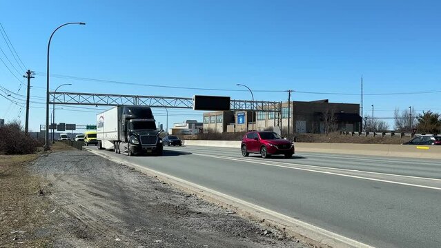 Cargo truck with cargo trailer driving on a highway. Truck delivers goods across the country of Canada on sunny clear day. Semi-trailer speeds along a motorway exit from the city of Halifax Canada. 
