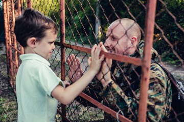 Dad and son holding hands after his return from the army. Soldier enjoying at home with his beautiful son. Soldier returning home and greeted by son lovingly.