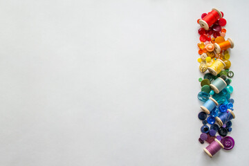 Buttons, colorful threads ,pins laid out on a white background as a rainbow spectrum. Copy space