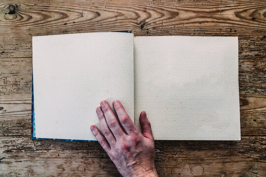 hand with ornamental notebook on wood