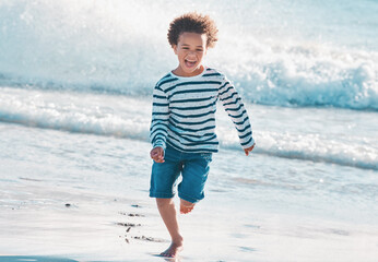 Im not letting the waves catch me. Shot of an adorable little boy running on the beach.