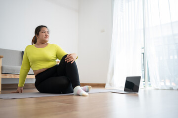 Asian overweight woman doing stretching exercise at home on fitness mat. Home activity training,...