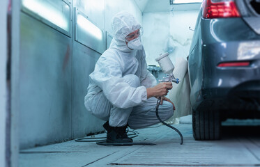 Mechanic painting car in chamber. Worker using spray gun and airbrush and painting a car, Garage...