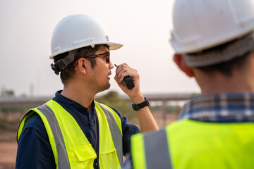 Close-up Architect and Civil Engineer checking work with walkie-talkie for communication to...