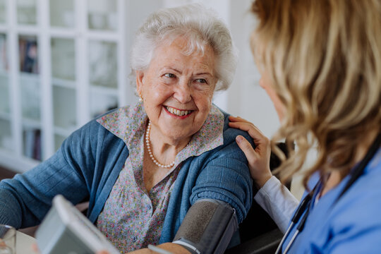 Nurse measuring blood pressuer to senior woman at her home.