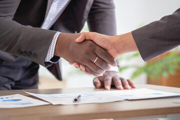 Satisfied black client shaking hands, thanking the manager for good financial deal African American businessmen shaking hands after successful business negotiations. Hiring. Buying services.
