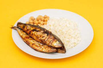 Grilled sardines with boiled rice and chick-pea on plate