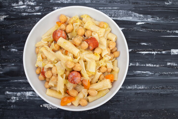 chick pea with smoked sausages, pasta and cabbage in white bowl