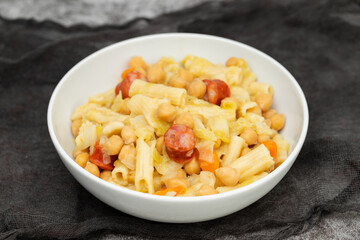 chick pea with smoked sausages, pasta and cabbage in white bowl