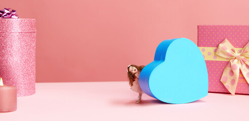 Little happy girl, child carrying giant, blue, heart shaped present box against pink background. Happy holidays, gifts. Concept of holidays, celebration, presents, greetings. sales. Copy space for ad