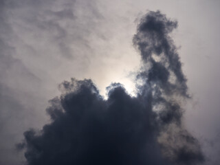 Sunlight behind ominous dark cloud in evening sky