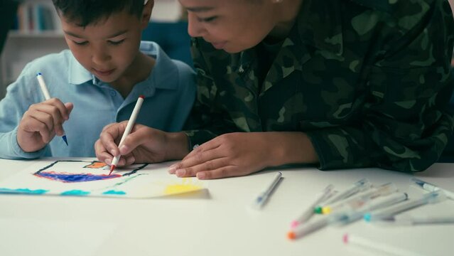 Closeup of cute little boy and his military mom drawing together, creative hobby