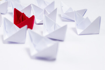 High angle shot of white paper boats defocused with one red boat in the middle.