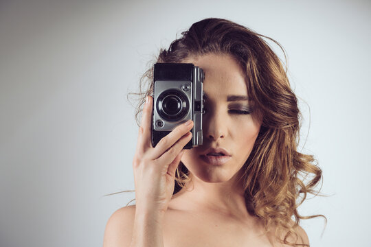 Nude woman with vintage photo camera