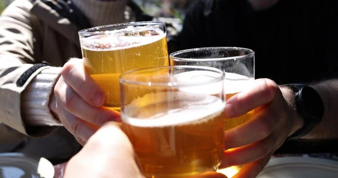 Group of friends enjoying beer in brewery pub outside. Hands of young people and a glass of beer