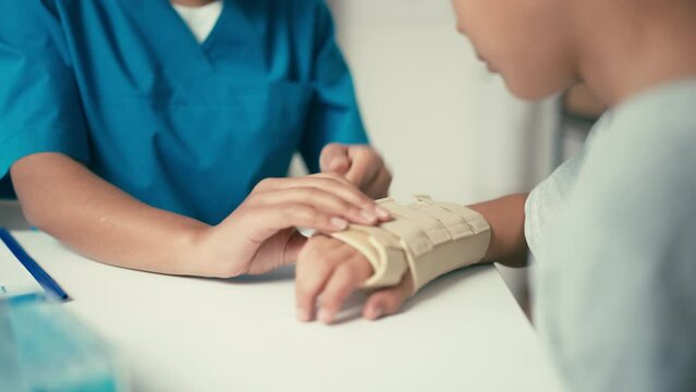 Close-up of doctor fixing cast to her little patient's hand, rehabilitation