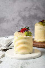 Cream cake surrounded by chocolate. Chocolate and fruit cake on gray background. Studio shoot. Bakery products. Close up