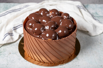 Chocolate covered profiteroles birthday cake. Chocolate cream cake on gray background. Close up