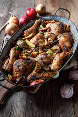 Braised chicken with onions and apples in a old fashioned roasting pan isolated on wooden table