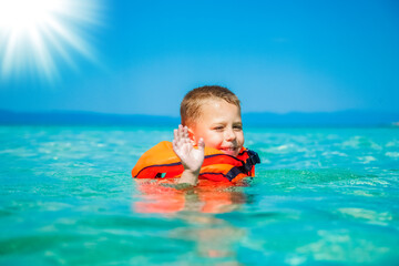 happy child in a vest at the sea playing